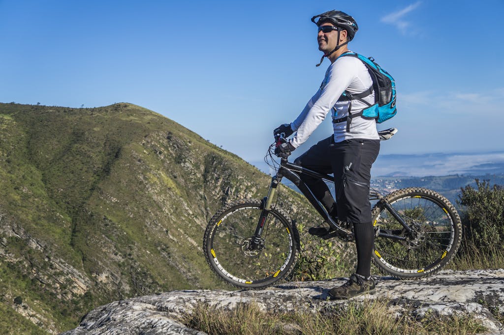 Exciting Things to Do in Halkidiki 11 Adult cyclist on mountain bike overlooking scenic rocky landscape under clear blue sky.