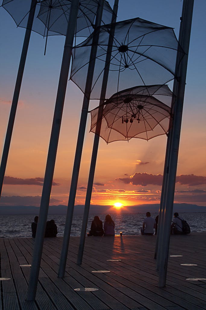 A breathtaking sunset at Thessaloniki with people enjoying the view by the iconic Umbrellas sculpture.