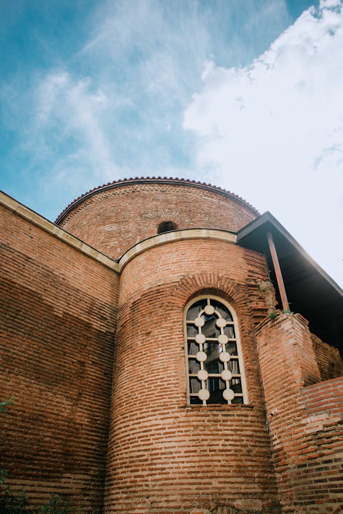 A close-up view of historic brick architecture featuring a circular window against a blue sky.