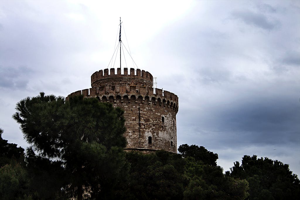 Explore the iconic White Tower, a renowned landmark in Thessaloniki under a cloudy sky.